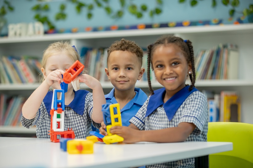 Three young students sitting at a desk with toys