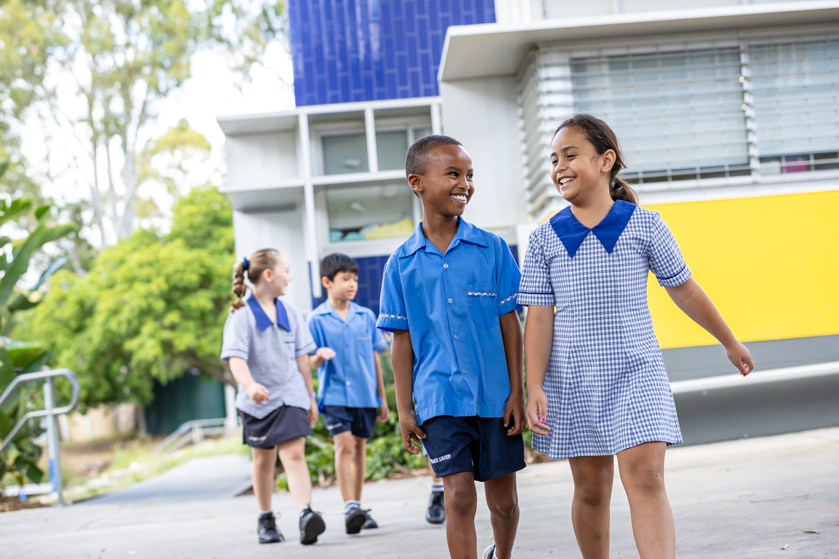 Two students walking outside in school grounds.
