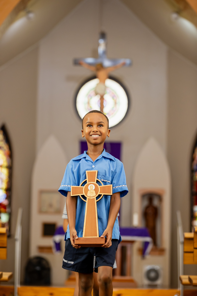 A student is standing in a church, holding a cross.