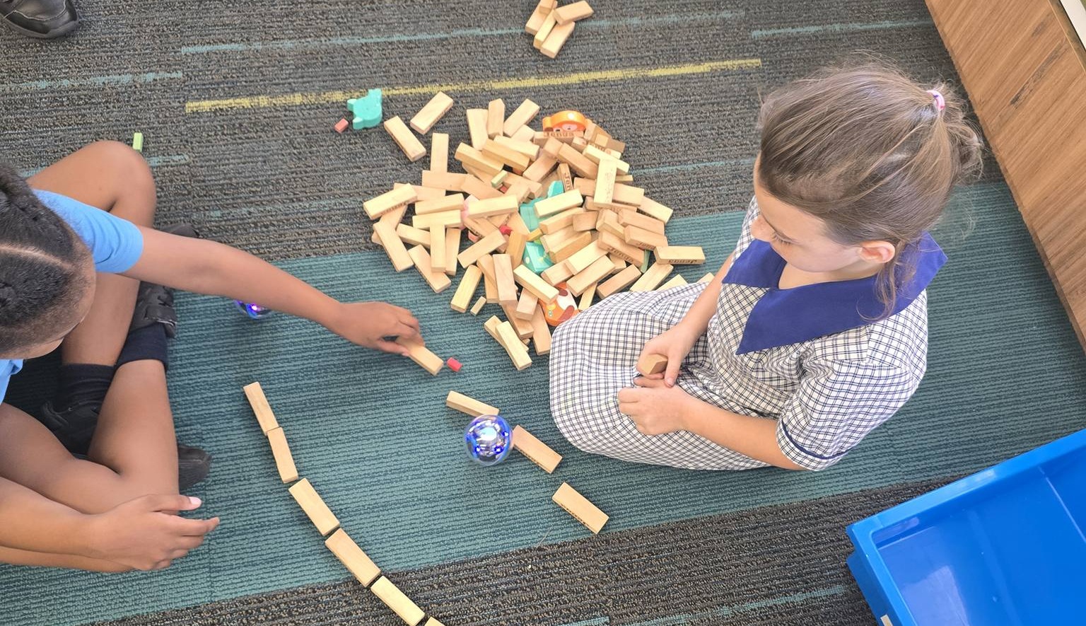Two students sitting on floor playing with blocks.